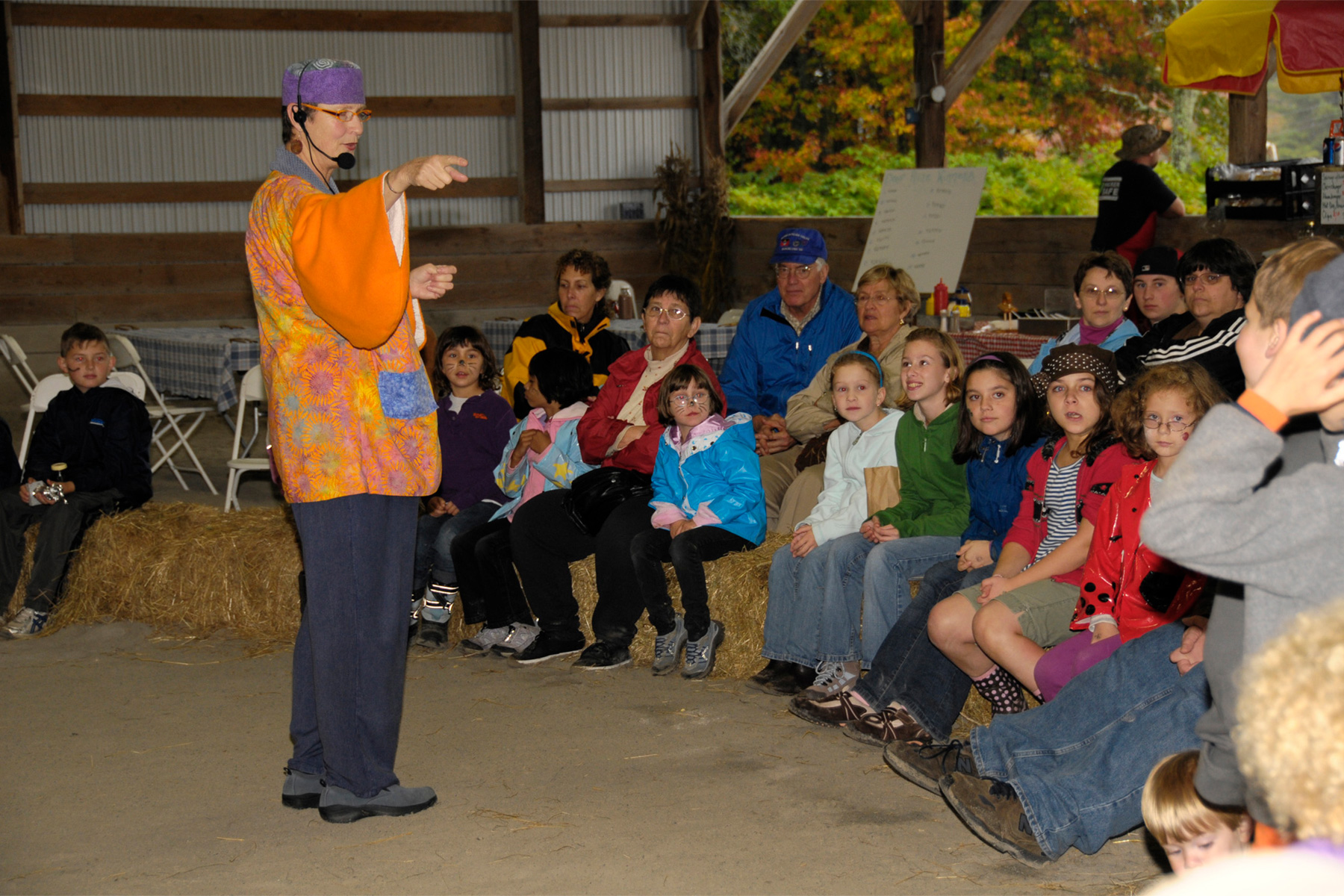 kids sitting on hale bales watchinga an entertainer